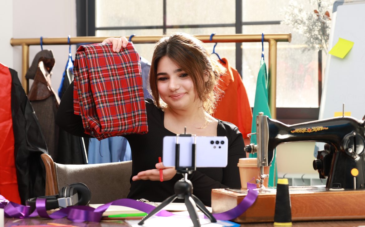 Cute tailor showing her fabric to the phone